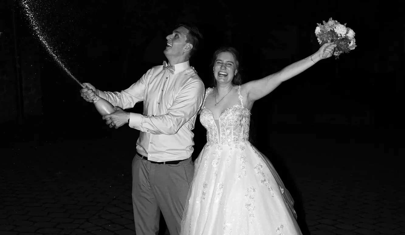 Hochzeitspaar in Driburg Brautpaar feiert mit Sekt in Bad Driburg, sie lächeln und die Braut hält einen Blumenstrauß in der Hand.