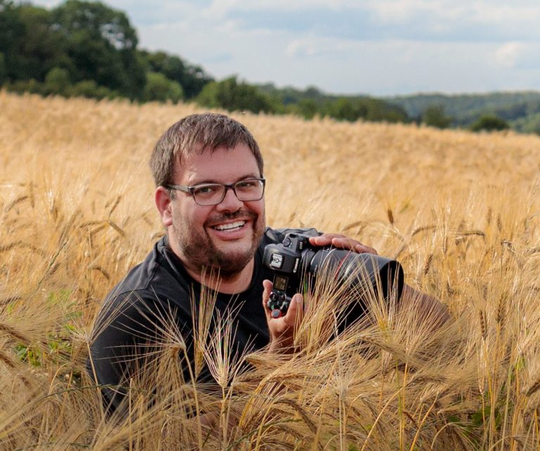 Kevin Brand mit Kamera in einem Weizenfeld bei einer Hochzeit in Bad Driburg-Höxter